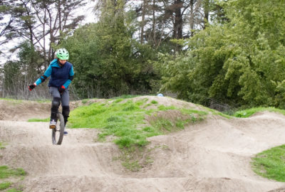 Mountain unicyclist cresting a small bump in a dirt pump track