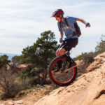 Woman riding mountain unicycle on steep red sandstone