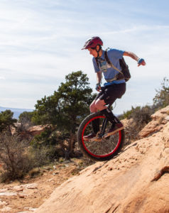 Woman riding mountain unicycle on steep red sandstone