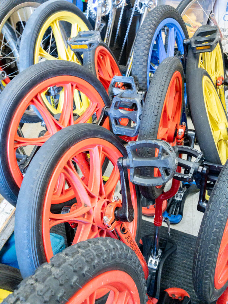 A pile of kid-sized unicycles with brightly colored wheels